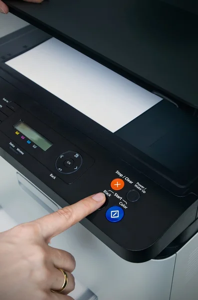 Woman switching on start button of laser printer — Stock Photo, Image