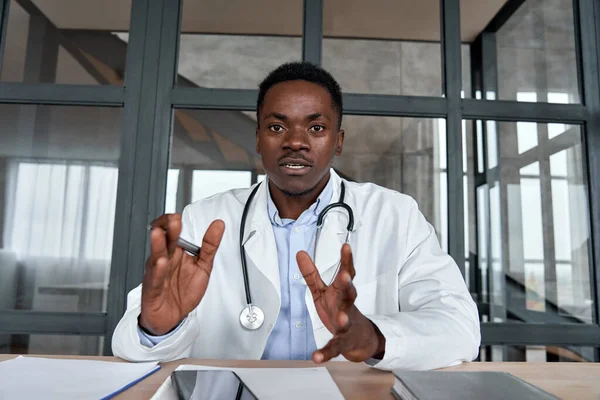 Black male doctor talking to web cam during virtual telemedicine advice.