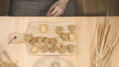 Şef ev yapımı zencefilli kurabiye üzerine şeker kreması yazıyor ve ahşap tepsiye koyuyor.