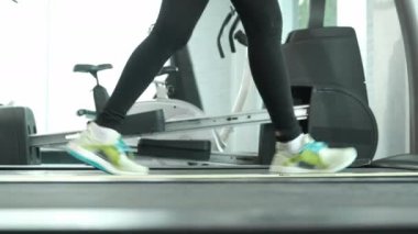 Koşu bandında koşan Asyalı kadın spor salonunda maraton antrenmanı yapıyor.