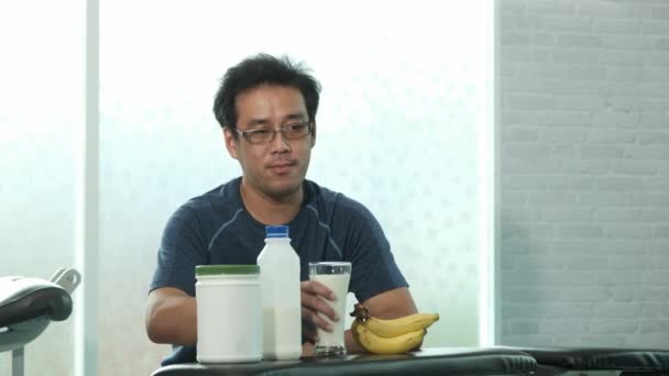 Νεαρός Ασιάτης Αθλητικά Κάθεται Και Πίνει Γάλα Μετά Την Προπόνηση — Αρχείο Βίντεο