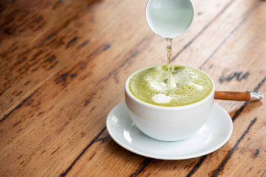 Beyaz seramik bardakta sıcak kibrit latte ya da yeşil çay, çay fincanı, çay fincanı, tarçın ve şeffaf şurup.