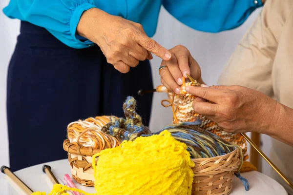 Happy senior elder woman teaching knitting woven craft other old female mature togehter at home as hobby. happiness retirement people