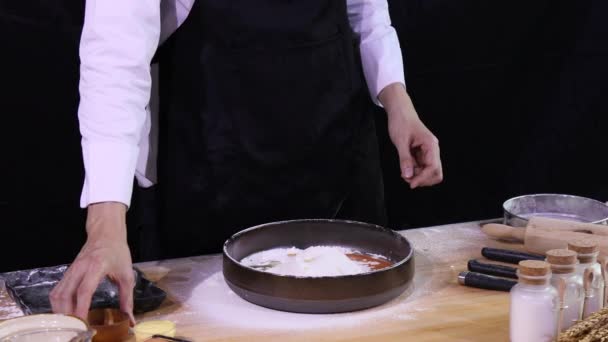 年轻的亚洲厨师在搅拌面团做面包之前 先拿起木杯 把盐倒入碗中的面包粉 — 图库视频影像