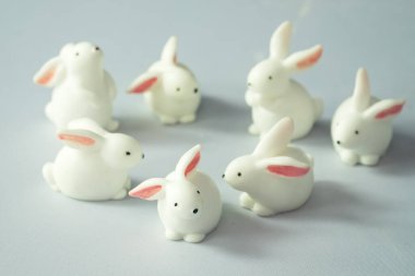 Minyatür beyaz tavşan oyuncağı beyaz arka planda daire şeklinde bir çok eylem oluşturur 