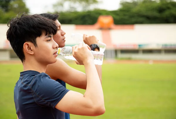 Zamknąć Dwóch Azjatyckich Nastolatków Pijących Wodę Butelki Bieganiu Parku Fitness — Zdjęcie stockowe
