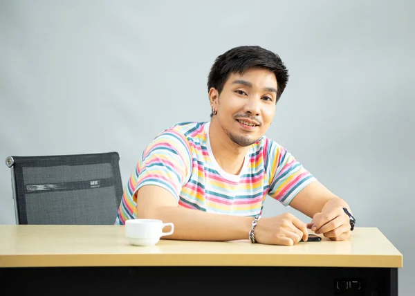 漂亮而严肃的男模肖像画穿着彩虹T恤坐在客厅里微笑 — 图库照片