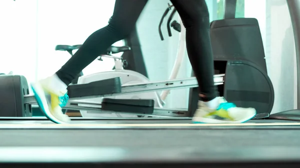 Foot Fitness Asyalı kadın ısınıyor ve koşu bandında koşuyor. Yan kamera, spor salonunda maraton koşuları eğitimi.