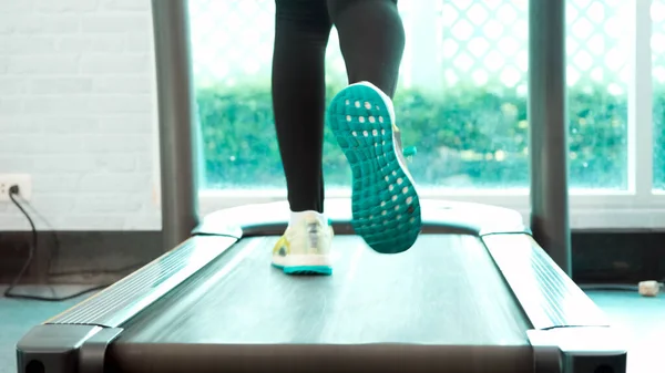 Foot Fitness Asyalı kadın ısınıyor ve koşu bandında koşuyor. Dikiz kamerası, spor salonunda maraton koşuları eğitimi.