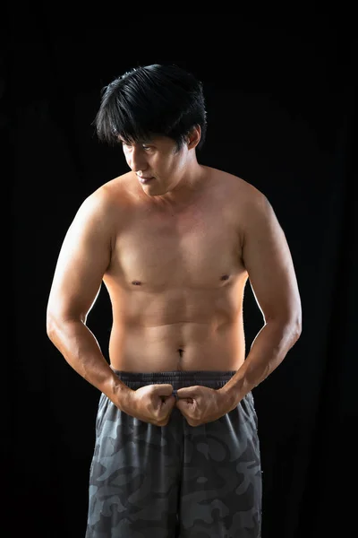若いですアジア人男性無慈悲なネイティブパンツポーズ強い体の筋肉上の黒の背景 — ストック写真