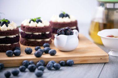 Böğürtlenleri birlikte kapayın. Tahtadaki üç sıra kakaolu kek.