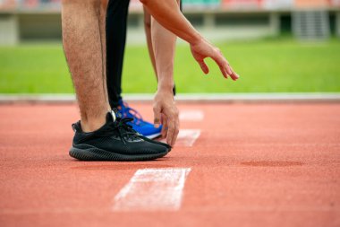 Açık alanda başlangıç çizgisinde iki erkek koşucuyu kapatıyoruz. Bacaklar ve eller üzerinde yoğunlaşıyoruz. Hazırlık kararlılığını ve atletik yarışma konseptini göstermeye hazırız.