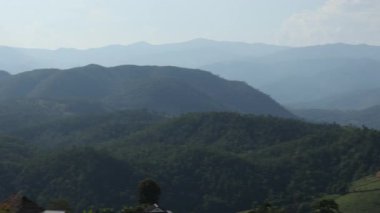 Kırsal kesimde, yumuşak gün ışığı altında puslu dağ katmanlarının çekim gücü seyahat, arka plan ve çevre kavramları için huzurlu ve rüya gibi doğal bir manzara yaratıyor.