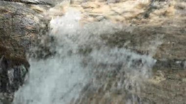 Şelalenin doğal kayaların üzerine sıçraması, hareketin, enerjinin ve arka planda, doğa temalarında veya eko kavramlarında kullanılmak üzere taze dokunun yakalanması.