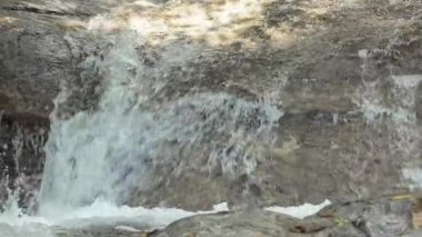 Doğal kayaların üzerinden akan taze şelalenin yakın görüntüsü hareket ve doku gösteriyor. Arkaplan, çevre temalı tasarımlar ve refahla ilgili görsel kavramlar için mükemmel.