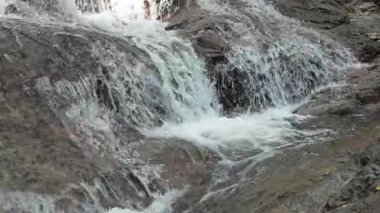 Şelaleyi, beyaz köpüklü su ve güçlü akışla birlikte doğal kayaların üzerine yakın çekim. Spa temaları, doğa kavramları, arka planlar ve ekolojik tasarımlar için mükemmel