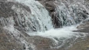 Katmanlı şelale yumuşak beyaz köpükle kayaların üzerinden yavaşça dökülüyor. Doğa geçmişi, spa temaları, refah içeriği ve çevre projeleri için ideal