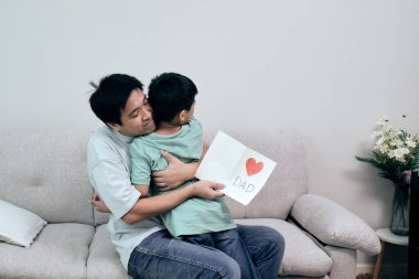 Asyalı baba, elinde kırmızı kalpli ve içinde 