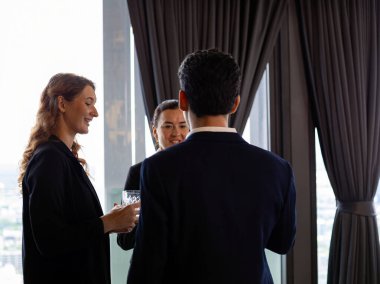 Modern ofisin penceresinin yanında iletişim kurmak ve sohbet etmek için bir araya gelen üç profesyonel iş adamı iletişim kurmak için güven takım çalışması ve kurumsal kültür gösteriyorlar.