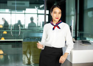 Kendine güvenen kadın havayolu çalışanları modern kontrolde, uçuş kartlarını tutuyor. Yolcuları çağdaş konukseverlik ortamında karşılıyorlar.