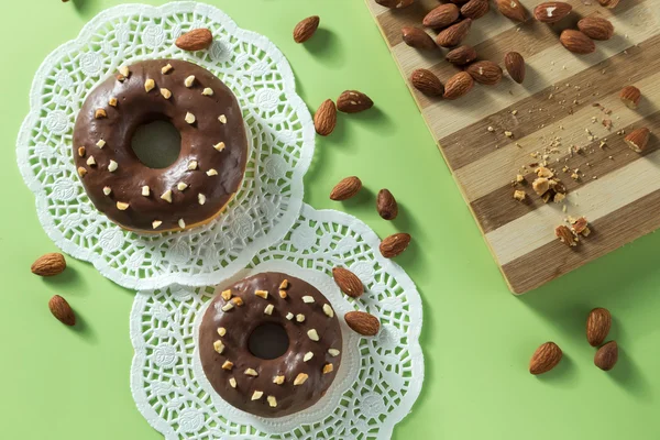 Donuts de chocolate saborosos em um fundo verde com amêndoas — Fotografia de Stock