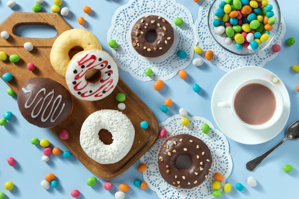 Donuts saborosos com frutas e doces na mesa — Fotografia de Stock