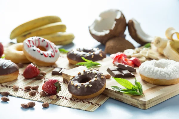 Tasty donuts with fruit and nuts on the table — Stock Photo, Image