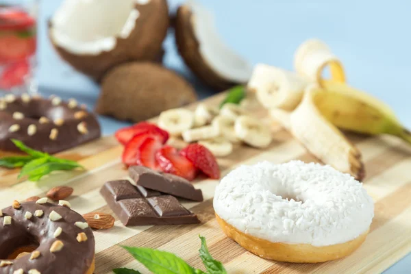 Donuts saborosos com frutas e nozes na mesa — Fotografia de Stock