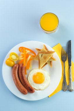 Nefis bir kahvaltı. Tereyağı, portakal suyu, reçel, bal, kruvasan, bıçak, çatal ile servis edilir. Sarı, mavi. Mavi arkaplan.