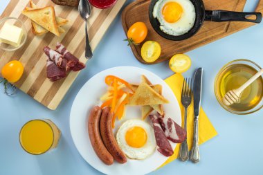 Nefis bir kahvaltı. Tereyağı, portakal suyu, reçel, bal, kruvasan, bıçak, çatal ile servis edilir. Sarı, mavi. Mavi arkaplan.