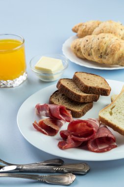 Nefis bir kahvaltı. Tereyağı, portakal suyu, reçel, bal, kruvasan, bıçak, çatal ile servis edilir. Sarı, mavi. Mavi arkaplan