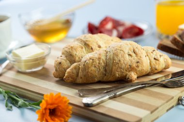 Nefis bir kahvaltı. Tereyağı, portakal suyu, reçel, bal, kruvasan, bıçak, çatal ile servis edilir. Sarı, mavi. Mavi arkaplan