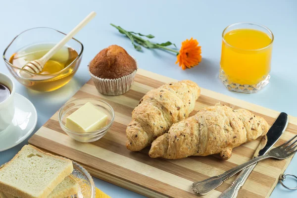 Nefis bir kahvaltı. Tereyağı, portakal suyu, reçel, bal, kruvasan, bıçak, çatal ile servis edilir. Sarı, mavi. Mavi arkaplan