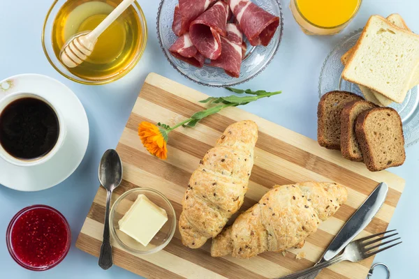 Nefis bir kahvaltı. Tereyağı, portakal suyu, reçel, bal, kruvasan, bıçak, çatal ile servis edilir. Sarı, mavi. Mavi arkaplan