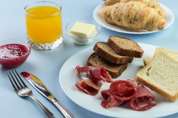 Nefis bir kahvaltı. Tereyağı, portakal suyu, reçel, bal, kruvasan, bıçak, çatal ile servis edilir. Sarı, mavi. Mavi arkaplan