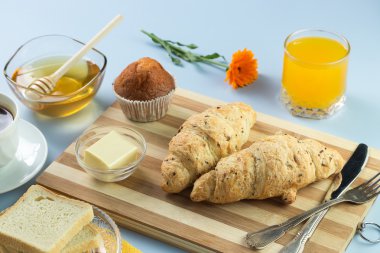 Nefis bir kahvaltı. Tereyağı, portakal suyu, reçel, bal, kruvasan, bıçak, çatal ile servis edilir. Sarı, mavi. Mavi arkaplan