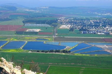 Gilboa Dağı 'ndan Jezreel Vadisi' ne (Megiddo Vadisi) doğa manzarası. Toprak sürme, renkli tarlalar, balık havuzları. İsrail 'de Aşağı Celile Bölgesi