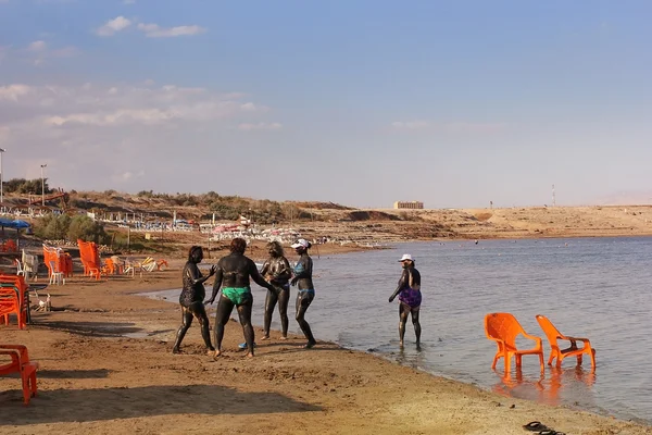 Les vacanciers dans la boue minérale de la mer Morte — Photo