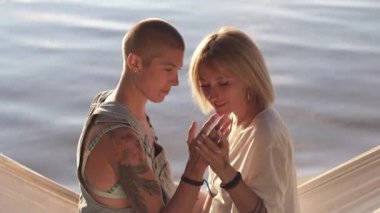 Hamakta sarılıp öpüşen kadın çift..