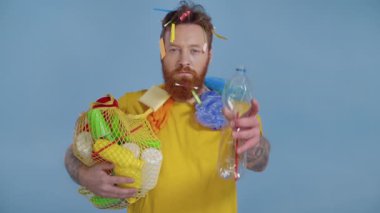 Elinde plastik çöp olan ve şişe sıkan bir adam. Yavaş çekim.