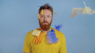 Sakallı adamın üzerine plastik çöp dökülüyor. Durup kameraya bakıyor. Yavaş çekim.