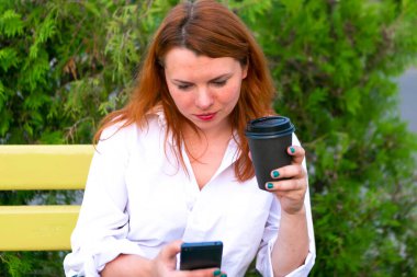 Kadın parkta kahve fincanı içiyor.