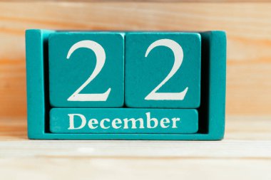 22 Aralık. Ahşap zemin üzerinde ay ve tarih olan mavi küp takvimi.