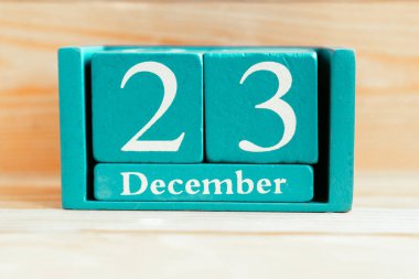 23 Aralık. Ahşap zemin üzerinde ay ve tarih olan mavi küp takvimi.