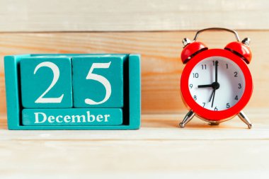 25 Aralık. Ahşap zemin üzerinde ay ve tarih olan mavi küp takvimi.