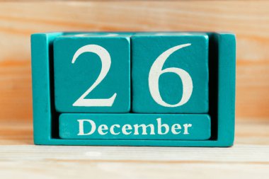 26 Aralık. Ahşap zemin üzerinde ay ve tarih olan mavi küp takvimi.