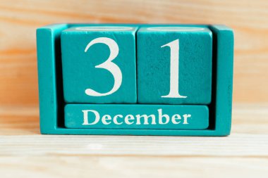 31 Aralık. Ahşap zemin üzerinde ay ve tarih olan mavi küp takvimi.