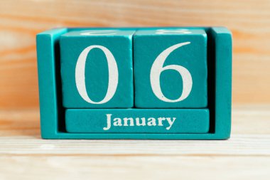 6 Ocak. Ahşap zemin üzerinde ay ve tarih olan mavi küp takvimi.