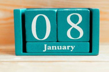 8 Ocak. Ahşap zemin üzerinde ay ve tarih olan mavi küp takvimi.