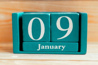 9 Ocak. Ahşap zemin üzerinde ay ve tarih olan mavi küp takvimi.